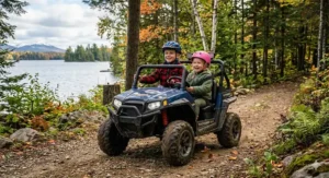 Child riding a green all-terrain kids' ATV across a grassy lawn.
