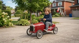 A young child driving a classic red pedal race car for kids on a suburban driveway in Canada. pedal tractor for toddlers