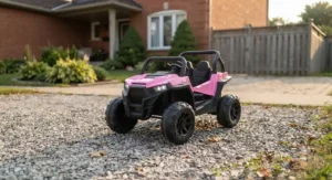 Pink kids electric off-road vehicle positioned on a suburban gravel driveway