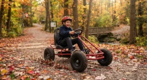 A child having fun driving a pedal-powered off-road go-kart through a Canadian park surrounded by autumn leaves.