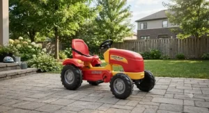 Sturdy pedal tractor for outdoor play designed with safety features, parked on a residential backyard patio.