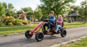 Brother and sister sharing a red two-seater pedal go-kart for siblings during a neighbourhood park outing.